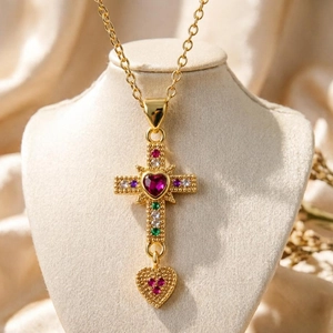 Golden cross necklace with colorful gemstones and heart pendant on a jewelry bust