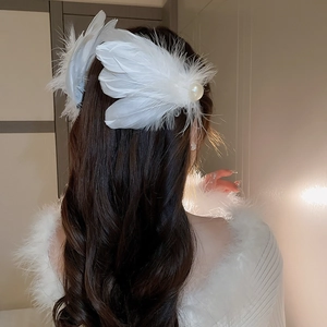 Detailed view of white feather hair clip with pearls worn on wavy brunette hair