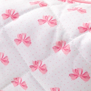 Détail du tissu matelassé blanc avec motifs nœuds roses et fermeture pour trousse