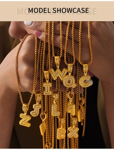 Close-up of gold box chain necklaces with sparkling zircon-studded letter pendants