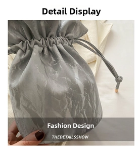 Detail showing marble-textured gray bucket bag with drawstring closure and metal accents