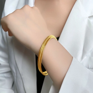 Three-piece golden minimalist bangle set featuring sandblasted and polished finishes