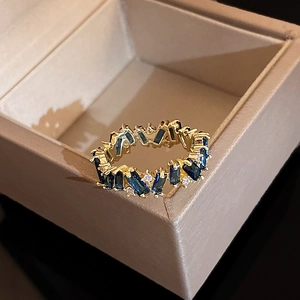 Close-up of gold-plated ring featuring an emerald-cut blue zircon on a jewelry box