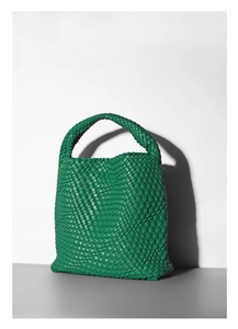 Close-up of green woven leather bucket bag showing intricate texture and top handle detail