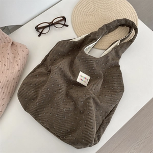 Macro view of brown corduroy tote bag showing floral patterns and interior lining detail