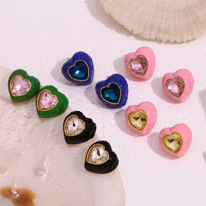 Détail macro de boucles d'oreilles cœur dorées 18K avec cristaux colorés et émail chic