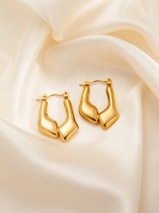 Close-up of golden stainless steel star earrings with twisted texture on silk