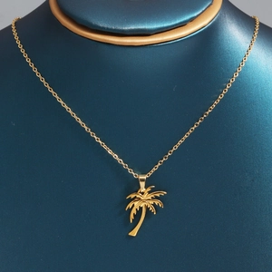 Golden coconut tree pendant necklace on display stand for a tropical vacation style