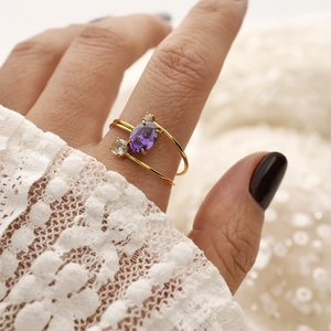 Detailansicht eines 18K goldfarbenen Doppelrings mit ovalem lila Zirkonia und Akzentsteinen