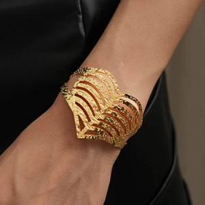 Modern gold hollow heart open cuff bracelet with hammered texture on a model's wrist