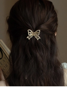 Detail of golden butterfly hair claw clip with white pearls on dark brown hair