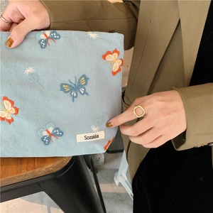 Close-up of sky blue canvas cosmetic bag featuring detailed butterfly and flower embroidery