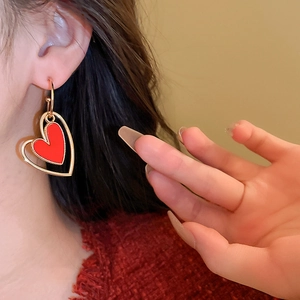 Macro detail of vintage hollow heart earring with vibrant red center on a female model