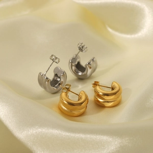 Double-layer gold and silver C-shaped stainless steel earrings on elegant satin