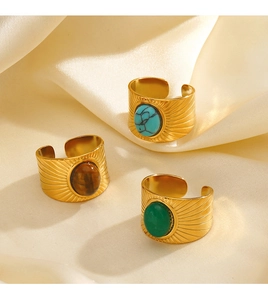 Detailed view of three gold rings with turquoise, tiger eye, and green stone insets