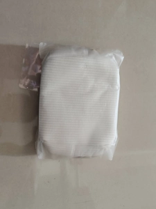 Detailed macro view of a white fabric makeup bag texture inside clear plastic packaging