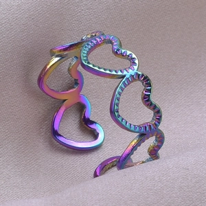Macro detail of rainbow heart hollow ring with colorful metallic finish on purple silk