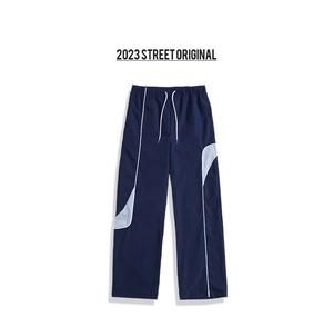 Detail of navy blue cargo pants featuring white contrast stitching and curved grey panels