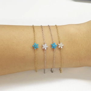 Detail of silver and gold flower bracelets with turquoise and zircon on a wrist