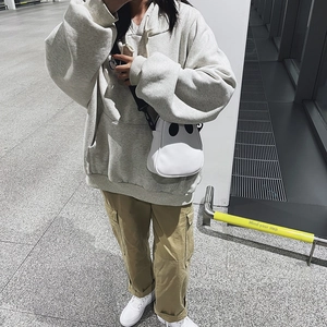 Street style view of white ghost-shaped crossbody bag with trendy oversized gray hoodie outfit