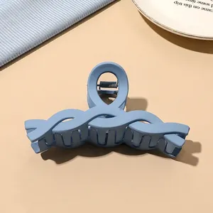 Detail of blue matte large hair claw clip with wave design on minimalist background