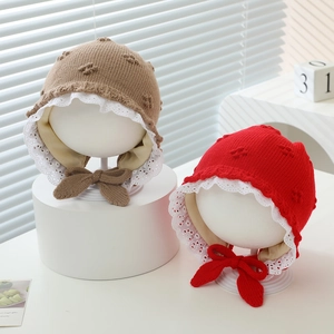 Detailed close-up of baby knit hats with delicate white lace trim and bow tie straps