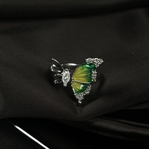 Detail of butterfly ring featuring yellow-green enamel and pavé crystals on black velvet