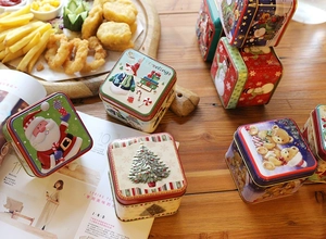 Macro detail of square Christmas tin boxes with embossed Santa and snowman holiday patterns