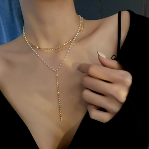 Detail view of multi-layer gold necklace with pearls and rhinestones on model