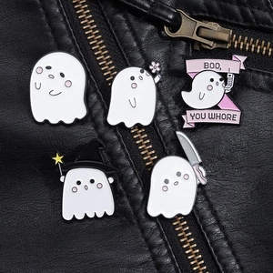 Close-up of five cute Halloween ghost enamel pins styled on a black leather jacket