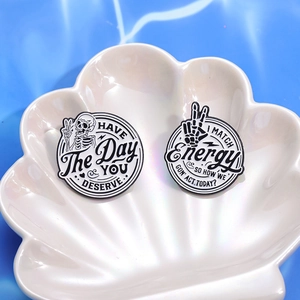 Black and white skeleton enamel pins with motivational quotes on a white shell tray