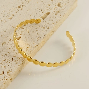 Detail of adjustable gold 18K stainless steel cuff bracelet with geometric round discs
