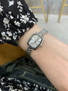 Close-up of elegant silver square watch with metal chain strap worn on the wrist