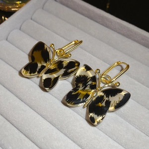 Close-up of golden butterfly earrings with acetate leopard print inlay in a velvet box