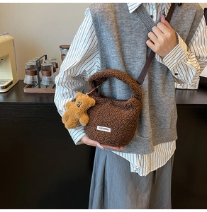 Detail of brown faux shearling bucket bag with bear charm and adjustable strap