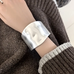 Detailed close-up showing the silver brushed metal texture of the wide open cuff bracelet