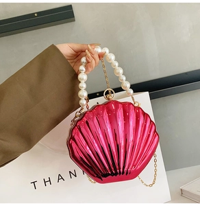 Macro view of metallic pink shell-shaped clutch bag with elegant large pearl handle