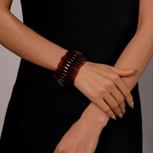 Détail d'un bracelet vintage en acrylique ambré à segments nervurés porté au poignet