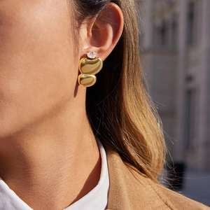 Classic gold egg-shaped stainless steel earrings with zircon inlay on model