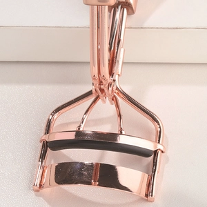 Macro shot of rose gold stainless steel eyelash curler head with black rubber pad
