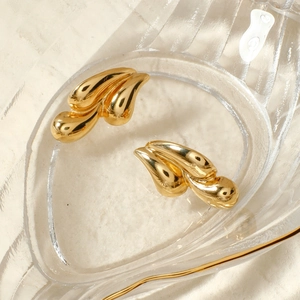 Elegant gold teardrop earrings with a polished finish on textured glass tray