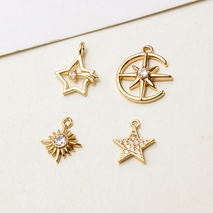 Detailed view of gold sun, moon, and star charms with sparkling cubic zirconia inlay