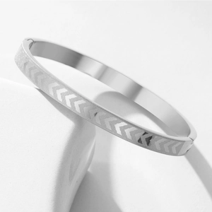 Detailed view of stainless steel bracelet featuring etched arrow patterns on silver metal