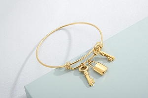 Detail of adjustable gold stainless steel bracelet with lock and two key pendants