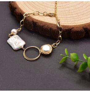 Detail of baroque pearl bracelet with gold chain on natural wood background display