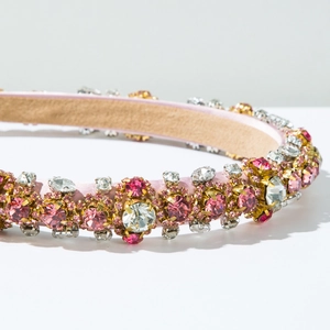 Detailed close-up of pink rhinestones and gold claws on a luxury velvet padded headband