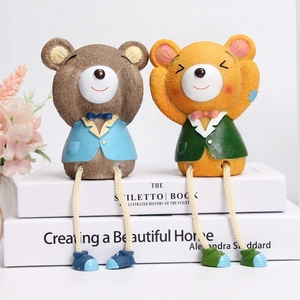 Three creative resin bear figurines with hanging legs sitting on books for home decor