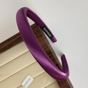 Detailed view of a purple padded satin headband on a premium wooden jewelry display tray