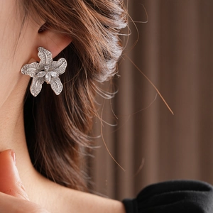 Detailaufnahme eines silbernen Blumensteckers mit funkelnden Zirkoniasteinen am Ohrmodell
