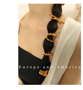 Detail of organic shaped gold-plated metal hair clips on a sleek ponytail hairstyle